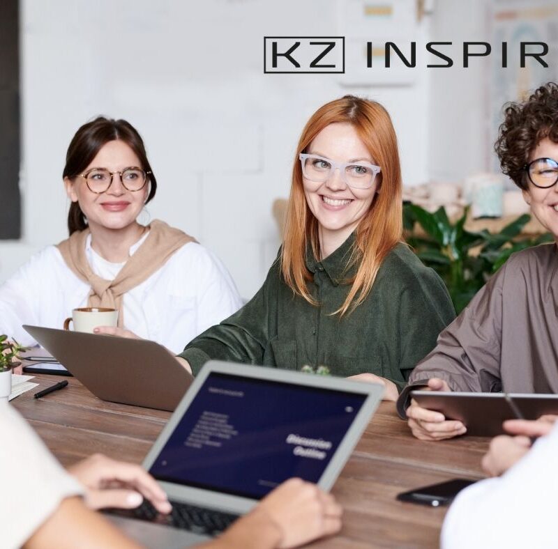 trzy uśmiechnięte kobiety w okularach na spotkaniu w biurze - czy wiek i doświadczenie to atuty na rynku pracy - KZ Inspire