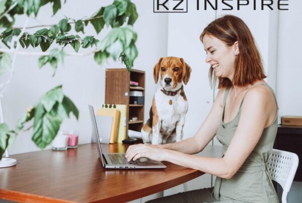 uśmiechnięta kobieta z psem siedząca przy biurku z otwartym laptopem - praca hybrydowa - co to znaczy- KZ Inspire