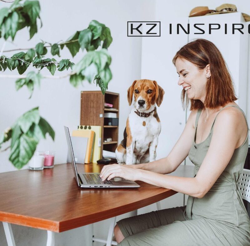 uśmiechnięta kobieta z psem siedząca przy biurku z otwartym laptopem - praca hybrydowa - co to znaczy- KZ Inspire